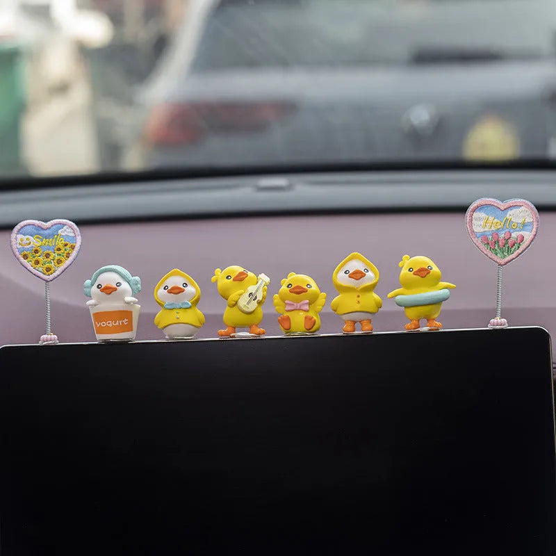 Set of six small yellow PVC duck figurines and one plastic sign for car dashboard decoration.