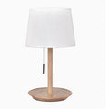Walnut coloured solid wood bedside lamp with white cloth shade on a table.