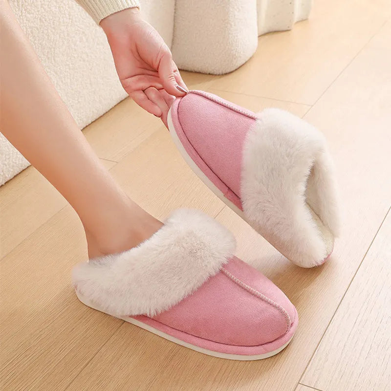 A pair of plush indoor slippers with a round toe, flat heel, and stitching detail, shown in one of five available colours.