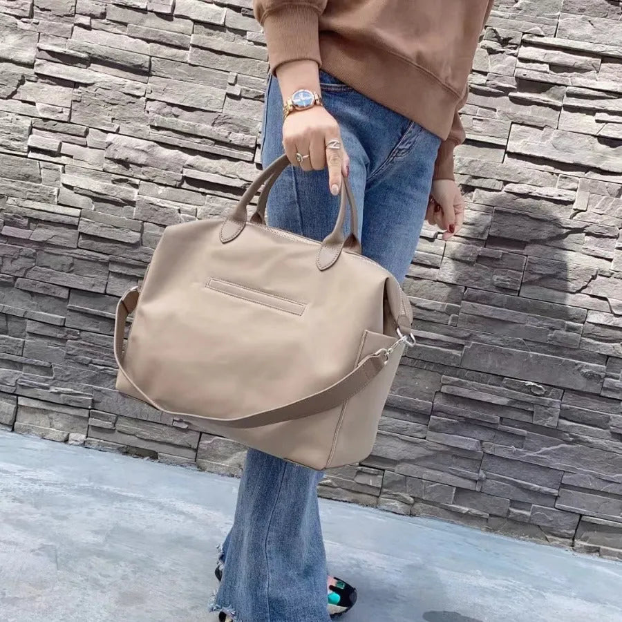 Black large capacity nylon waterproof shoulder bag with leather accents on a plain background.