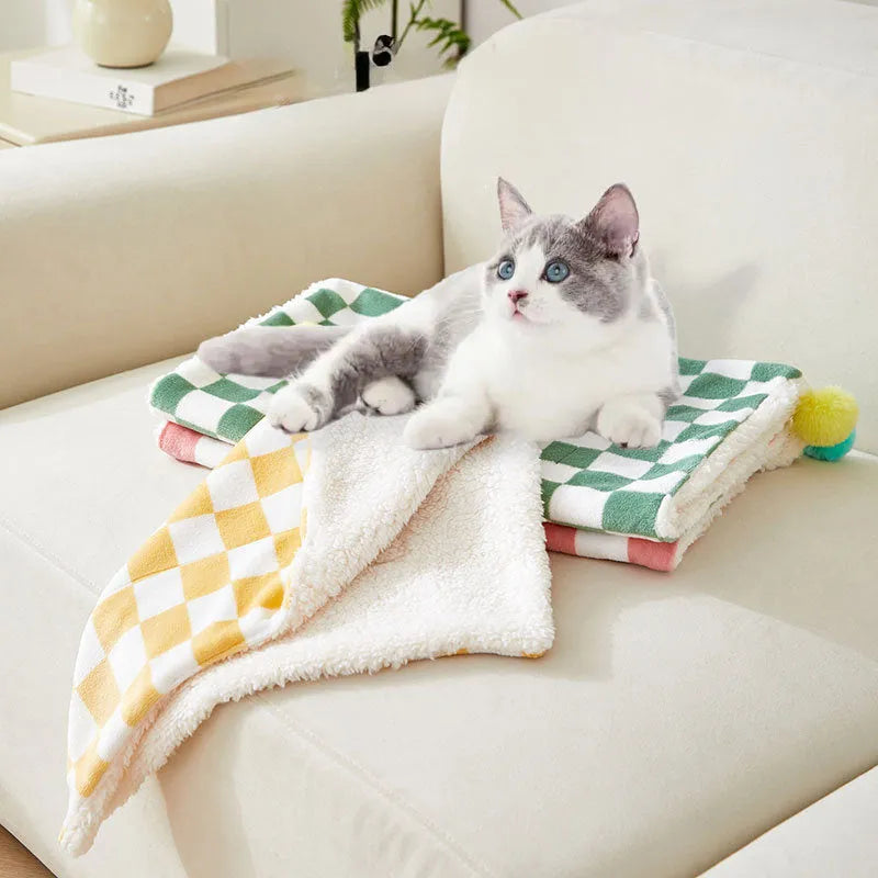 Plush pet blanket with bright plaid pattern and fur ball decorations for cats and dogs
