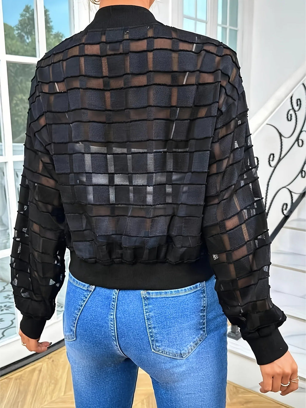 Black women's casual jacket with geometric pattern, full zip, and long sleeves on a hanger.