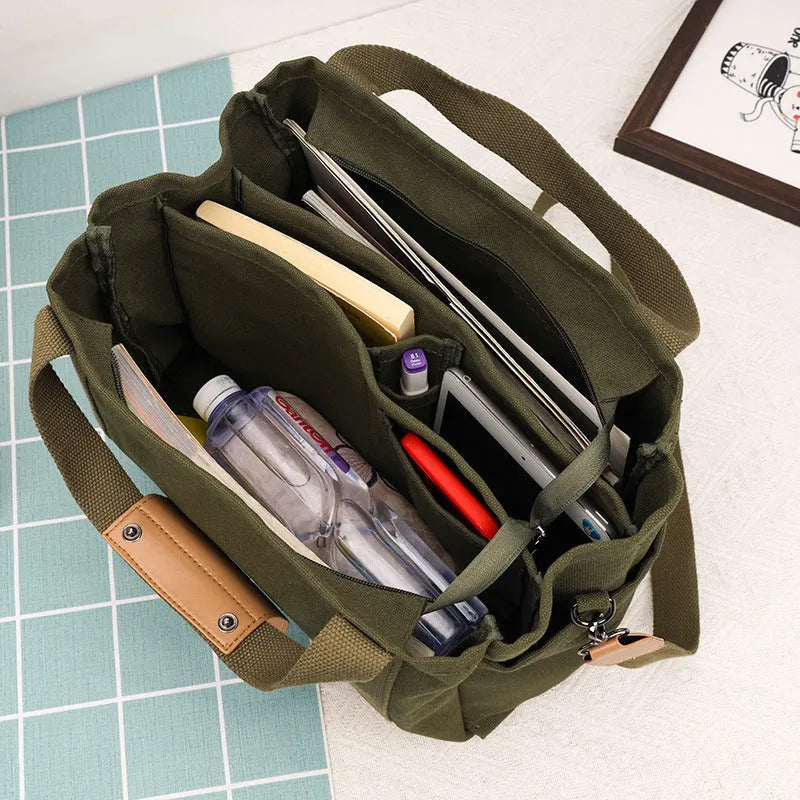 Large horizontal square canvas tote bag in army green with visible sewing lines and open zipper sides.