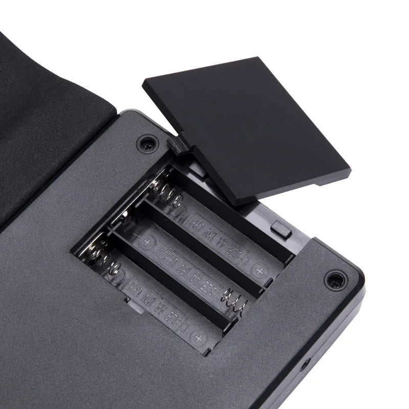 Portable black folding electronic keyboard rolled up next to its control panel and cable.