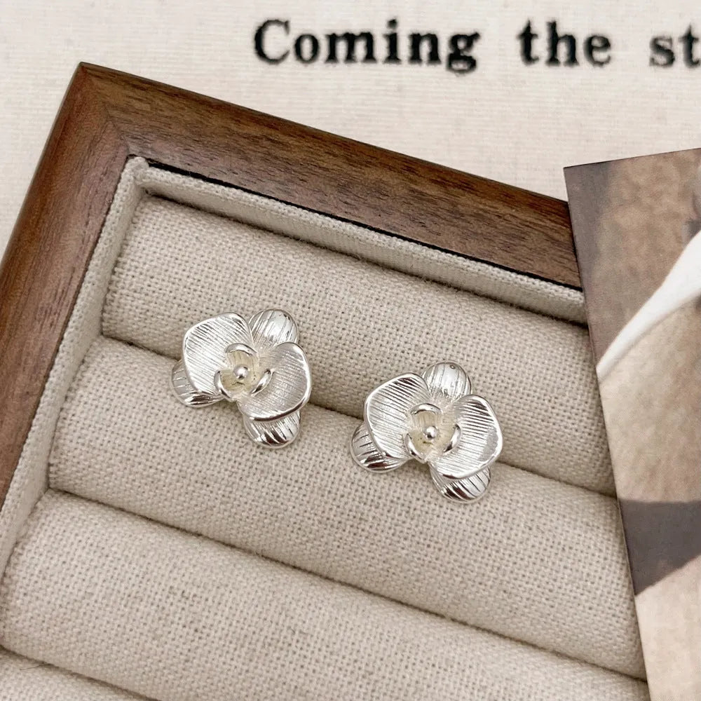A pair of gold and silver retro-style flower earrings with petal details on a white background.