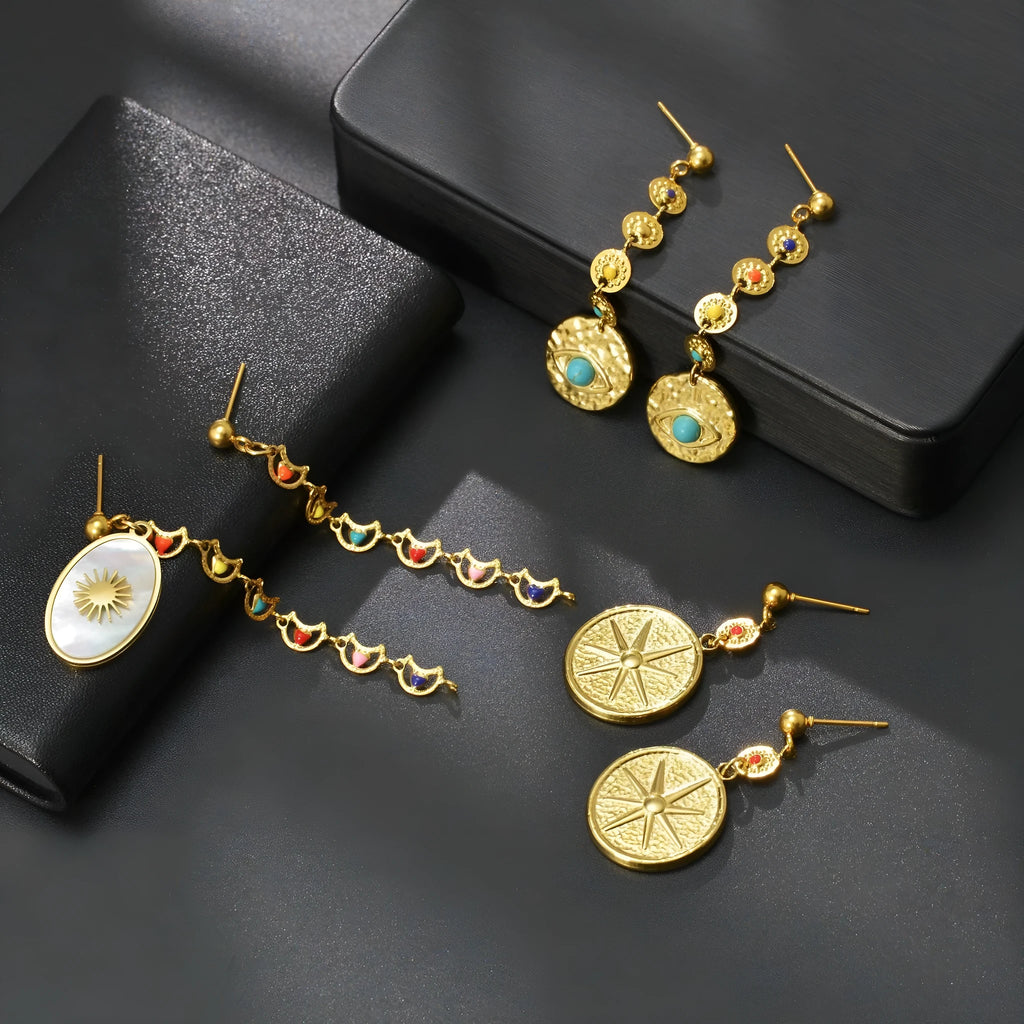 Geometric stainless steel drop earrings showing eight awn star, eye, and shell sun designs