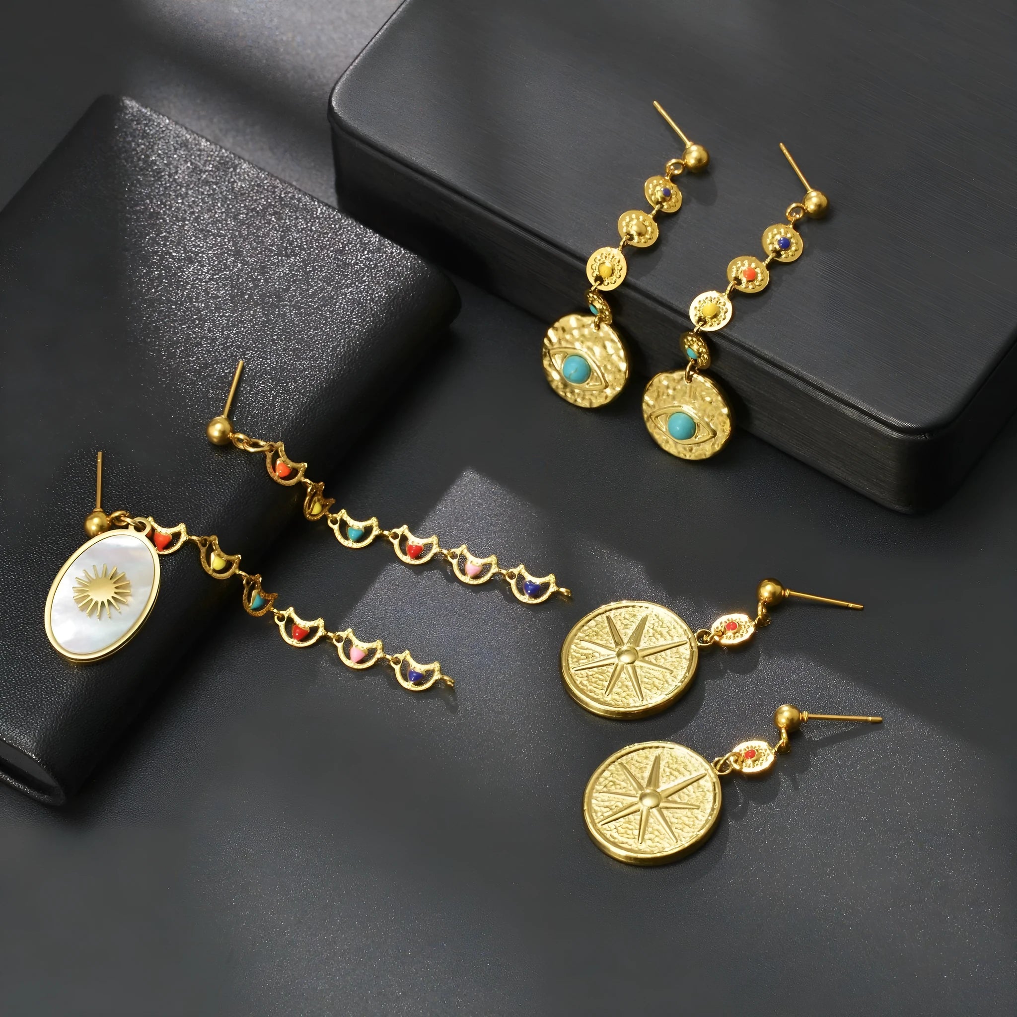 Geometric stainless steel drop earrings showing eight awn star, eye, and shell sun designs