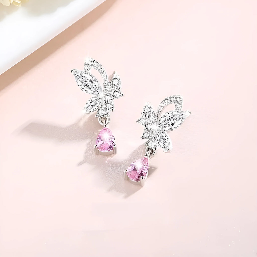 Close-up of a pair of silver butterfly stud earrings on a plain background.