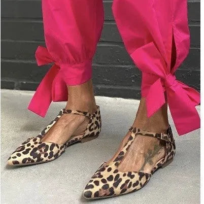 Leopard print women's pumps with pointed toe, cross straps, and a chunky low heel.