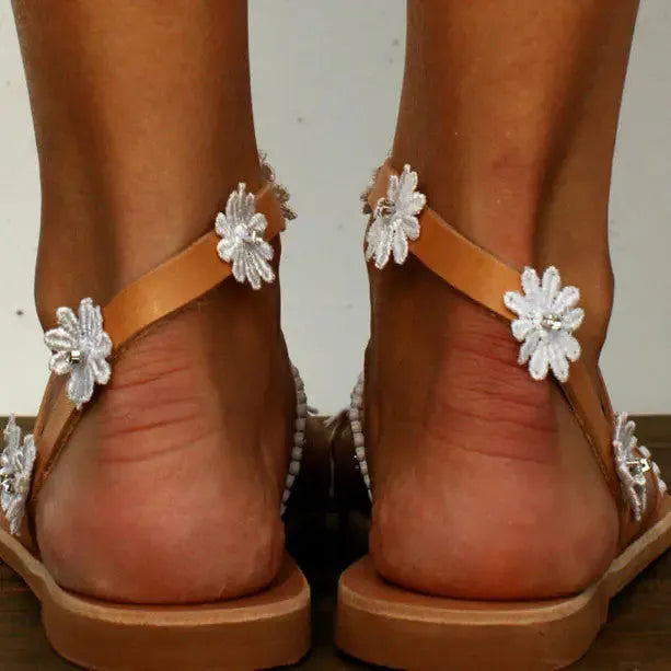 Brown women's Roman-style sandals with floral detail on the upper and a flat rubber sole.