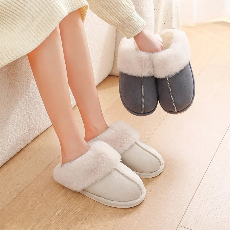 A pair of plush indoor slippers with a round toe, flat heel, and stitching detail, shown in one of five available colours.