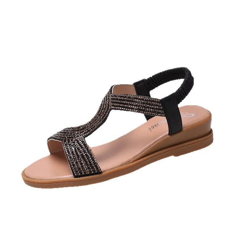 Gold women's patent leather sandals with rhinestone detailing and a non-slip sole on a sandy beach.