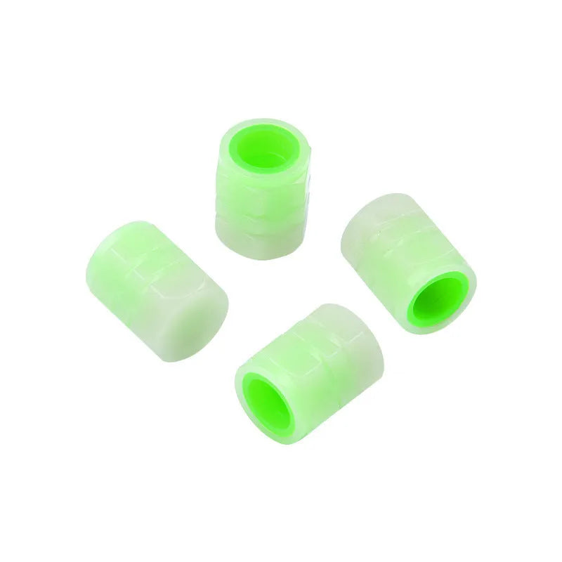 Set of four rubber luminous valve caps for car tyres on a dark background.