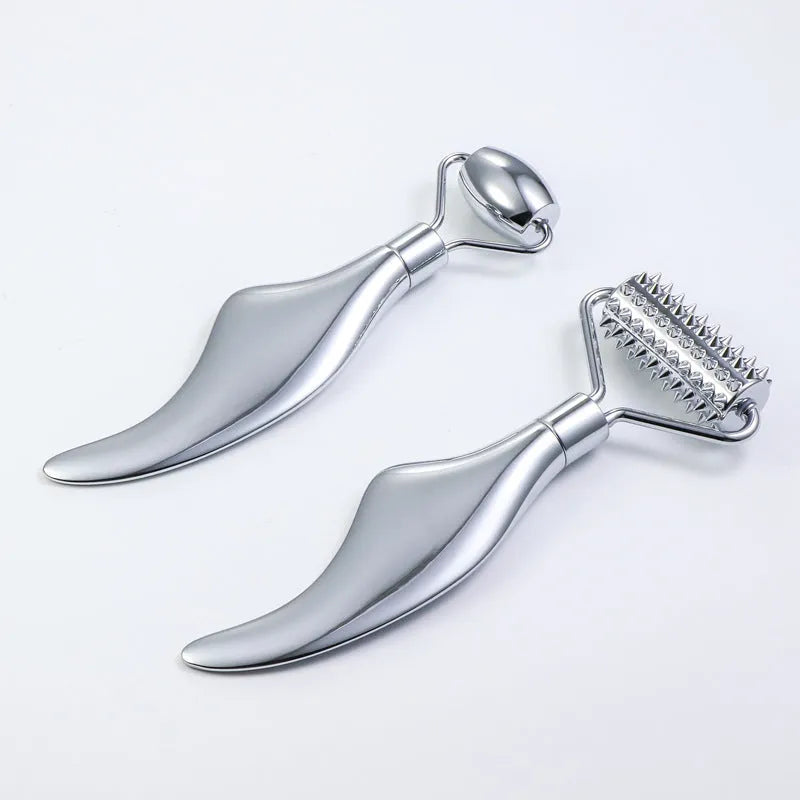 Stainless steel facial massage set showing a double-ended acupuncture pen with pointed tip and heart roller, plus a gua sha scraping plate.
