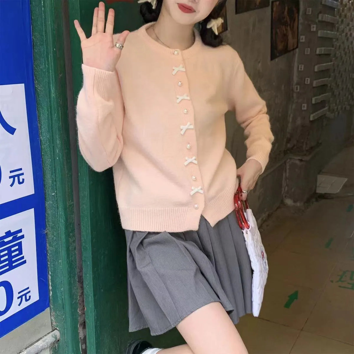 Women's light blue cardigan sweater with white bow pearl buttons fastened.