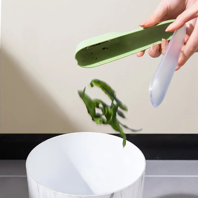 Dark green kitchen peeler with stainless steel blade stored inside its clear plastic storage tube.