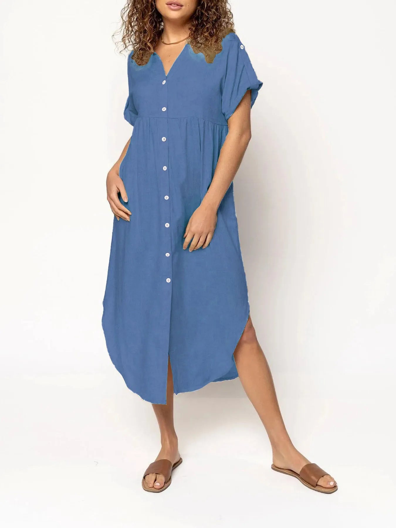 A woman wearing a loose-fitting, mid-length apricot-coloured casual dress with a button-down front.