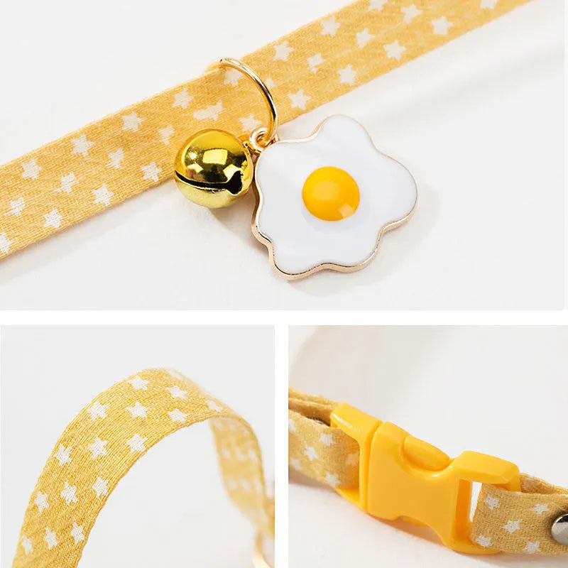 Green adjustable cat collar with a small bell and bow tie pendant on a white background.