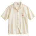 A light apricot men's shirt with a bamboo plant pattern and a relaxed Cuban collar.