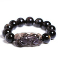 Polished natural crystal Pi Xiu bracelet with geometric ethnic design on a wrist.