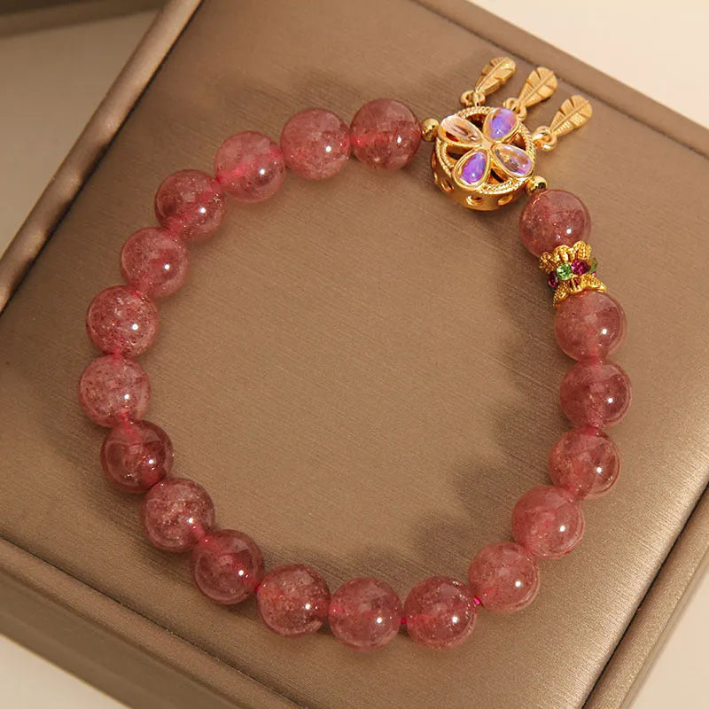 Women's strawberry quartz bracelet with four-leaf dream catcher ball pendant on wrist