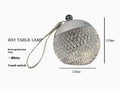 Small round touch-control dimmable LED night lamp in a metallic finish on a wooden table.