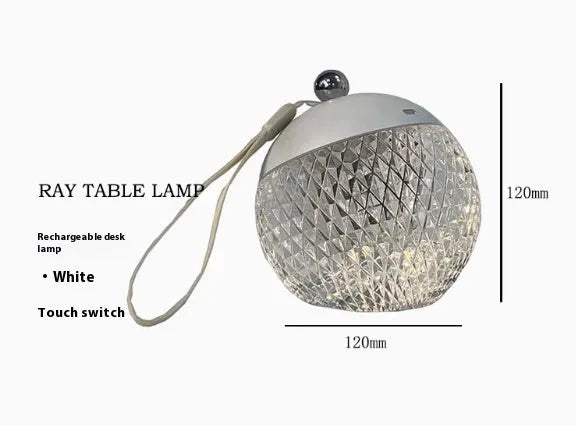 Small round touch-control dimmable LED night lamp in a metallic finish on a wooden table.