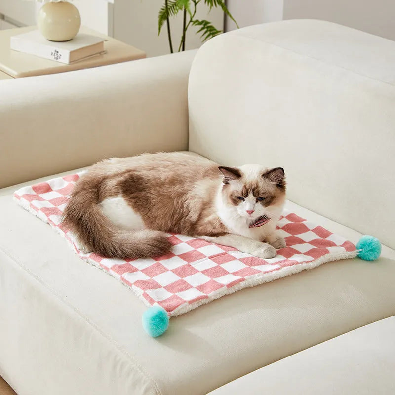 Plush pet blanket with bright plaid pattern and fur ball decorations for cats and dogs