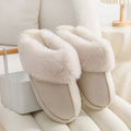A pair of plush indoor slippers with a round toe, flat heel, and stitching detail, shown in one of five available colours.