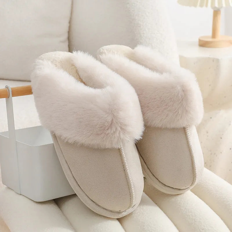 A pair of plush indoor slippers with a round toe, flat heel, and stitching detail, shown in one of five available colours.