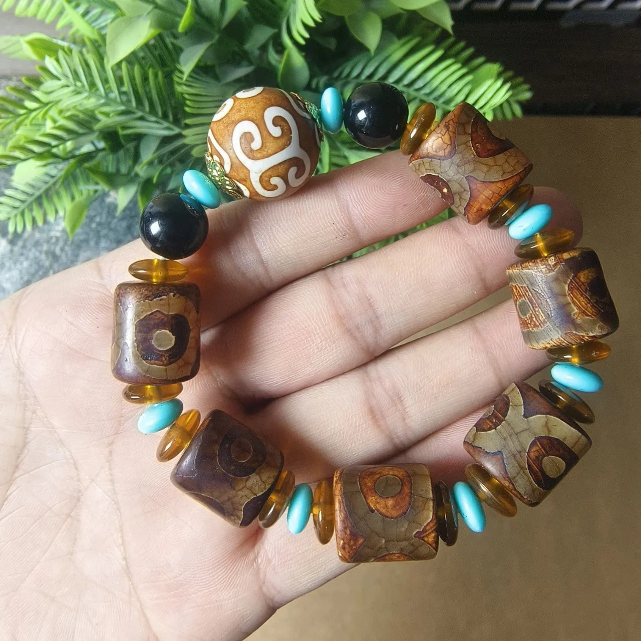 Distressed agate Tibetan bead bracelet with three-eye motifs and polished finish.