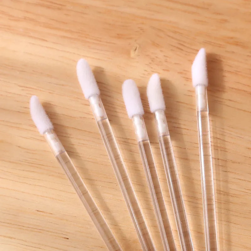 Pack of disposable flocked lip brush applicators with coloured handles on a white surface.