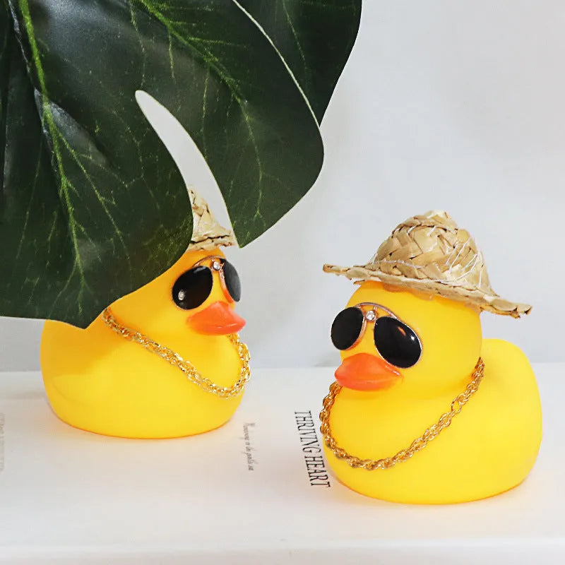 Yellow duck car ornament wearing straw hat with removable sunglasses necklace on dashboard