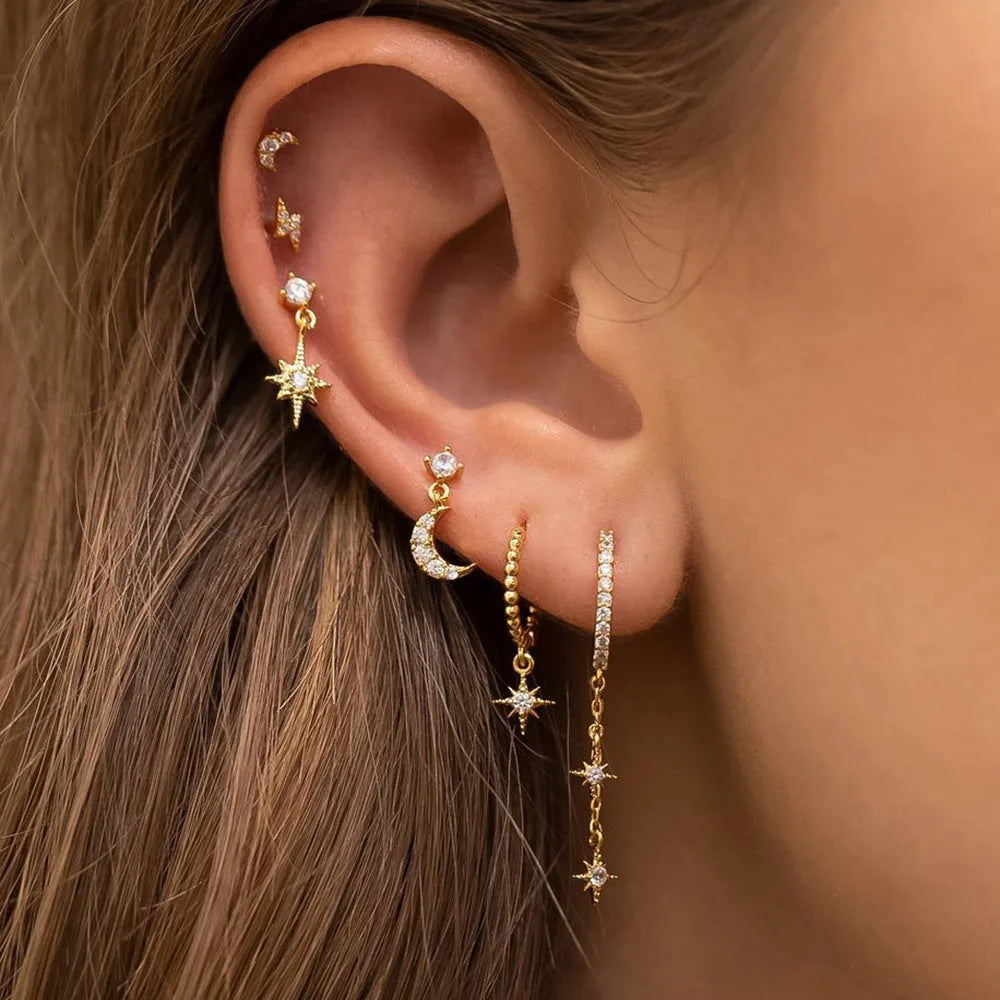 Six pairs of gold chain tassel earrings with zircon stones arranged in display