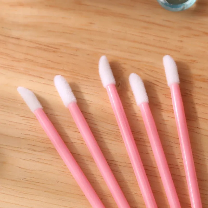 Pack of disposable flocked lip brush applicators with coloured handles on a white surface.