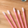 Pack of disposable flocked lip brush applicators with coloured handles on a white surface.
