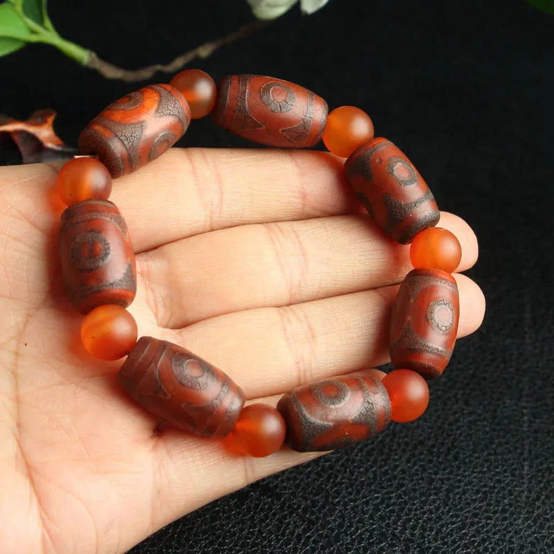 Distressed agate Tibetan bead bracelet with three-eye motifs and polished finish.
