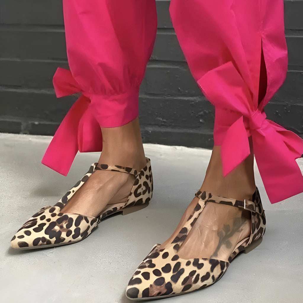 Leopard print women's pumps with pointed toe, cross straps, and a chunky low heel.