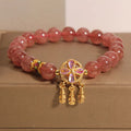 Women's strawberry quartz bracelet with four-leaf dream catcher ball pendant on wrist