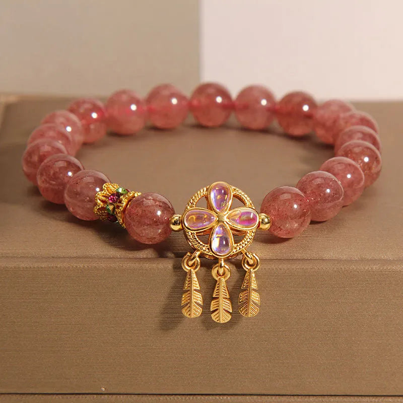 Women's strawberry quartz bracelet with four-leaf dream catcher ball pendant on wrist