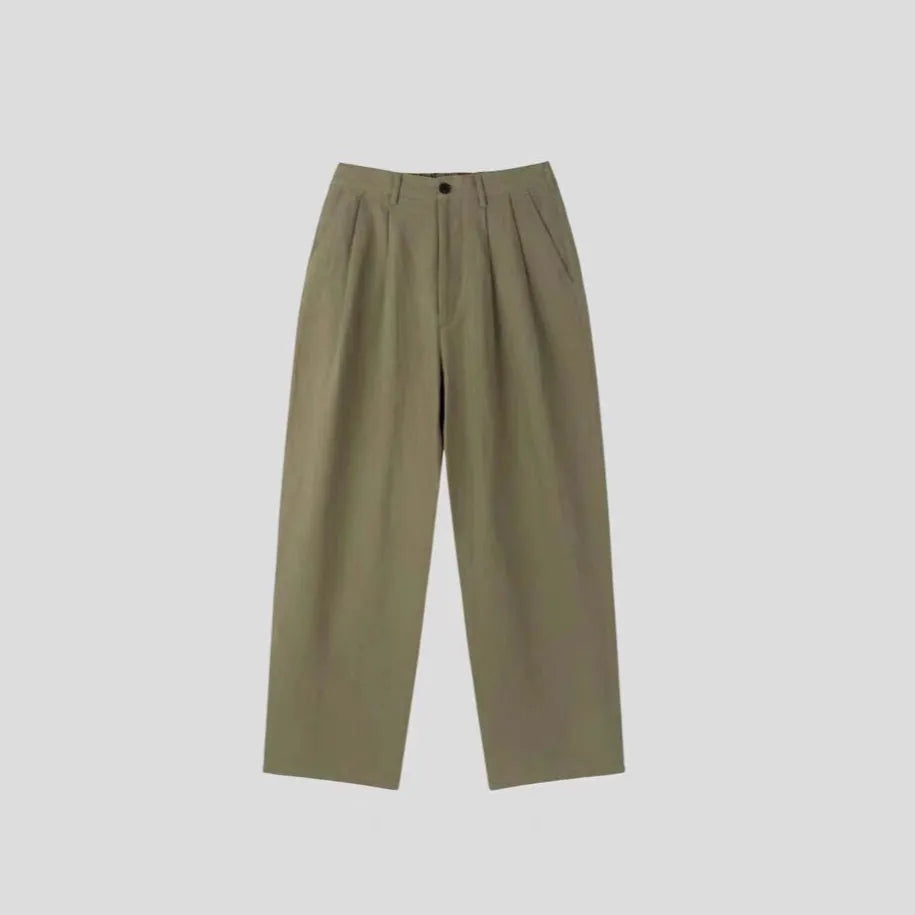 Man wearing loose fit apricot wide-leg cotton linen trousers with a zip fly and straight leg opening.