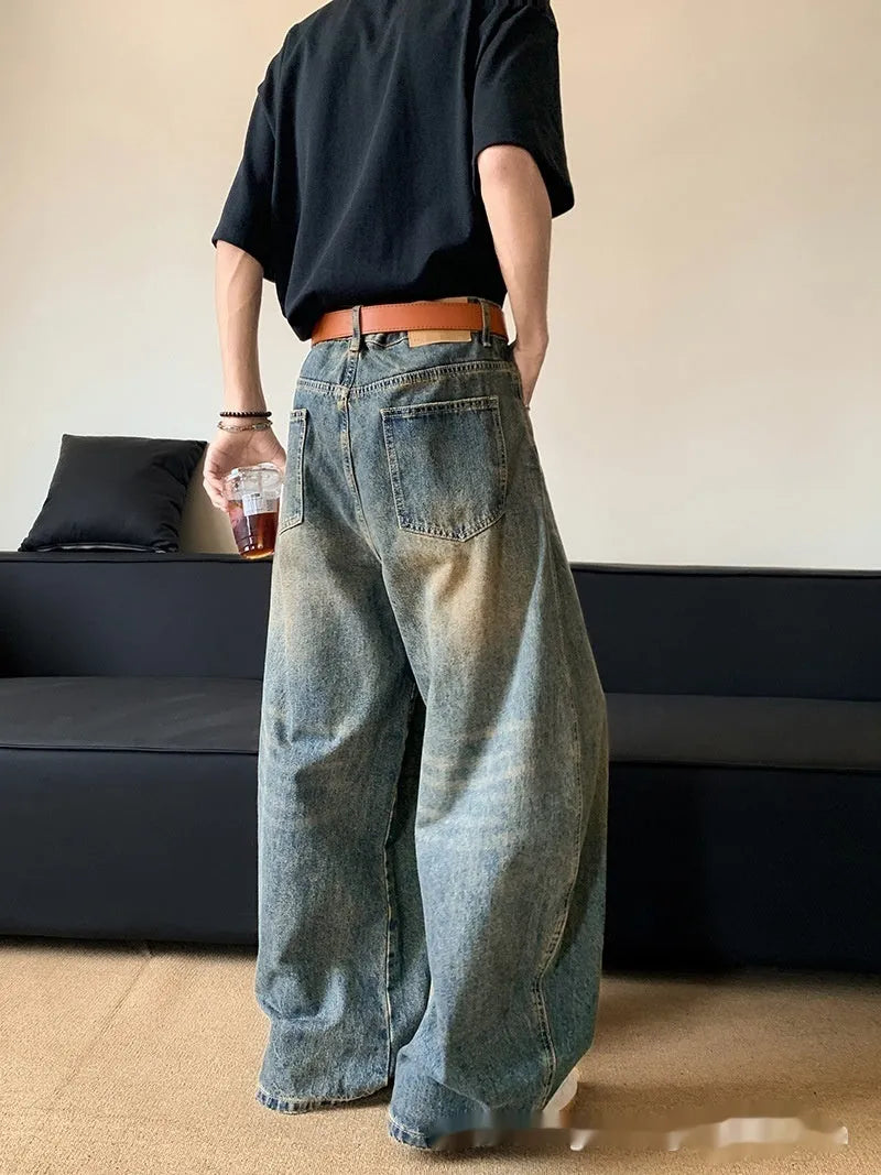 Men modelling retro blue distressed wide-leg jeans with machete detailing and a slimming fit.
