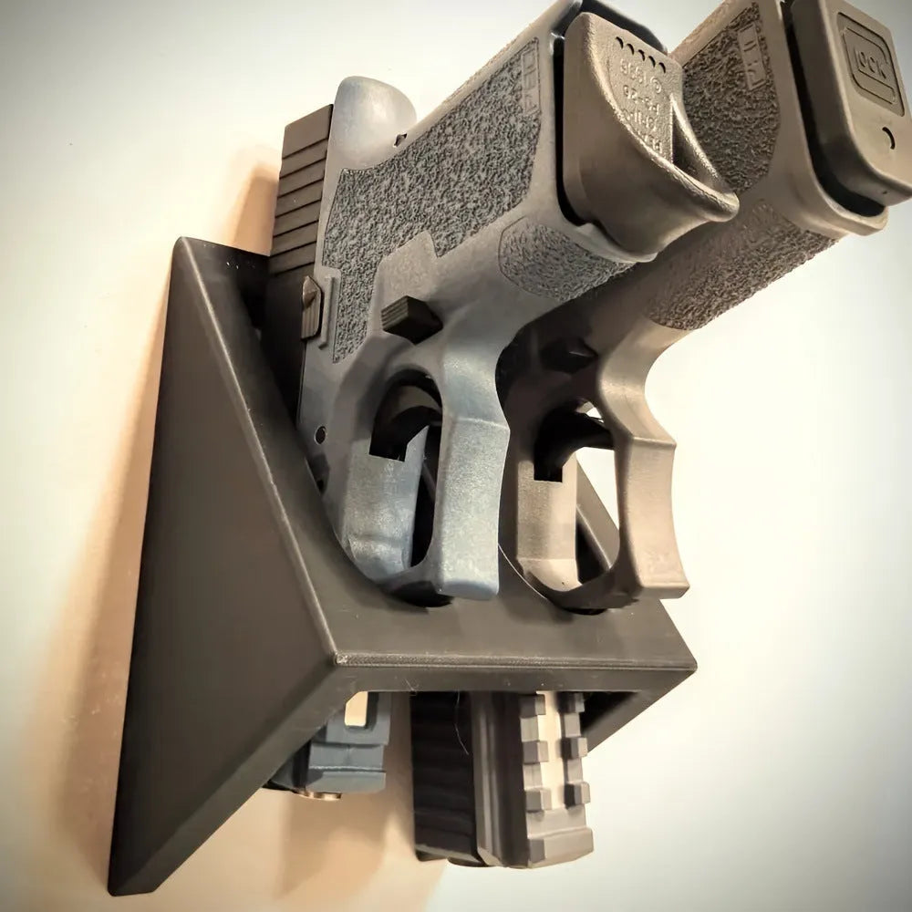 Black plastic pistol display stand for handguns and replicas on a flat surface.