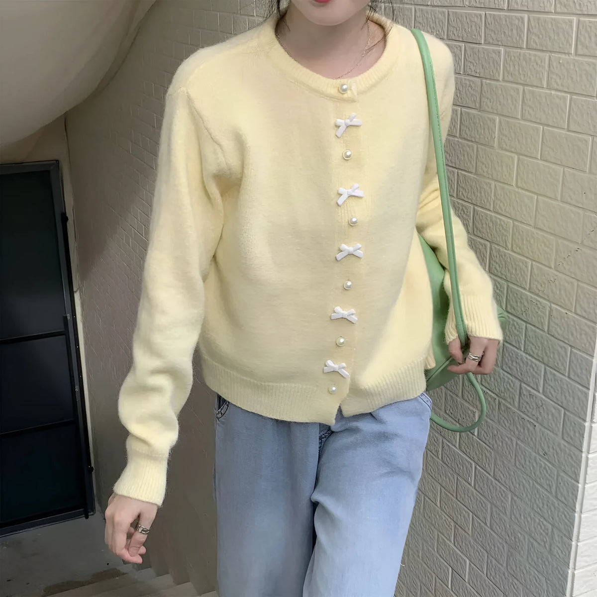 Women's light blue cardigan sweater with white bow pearl buttons fastened.