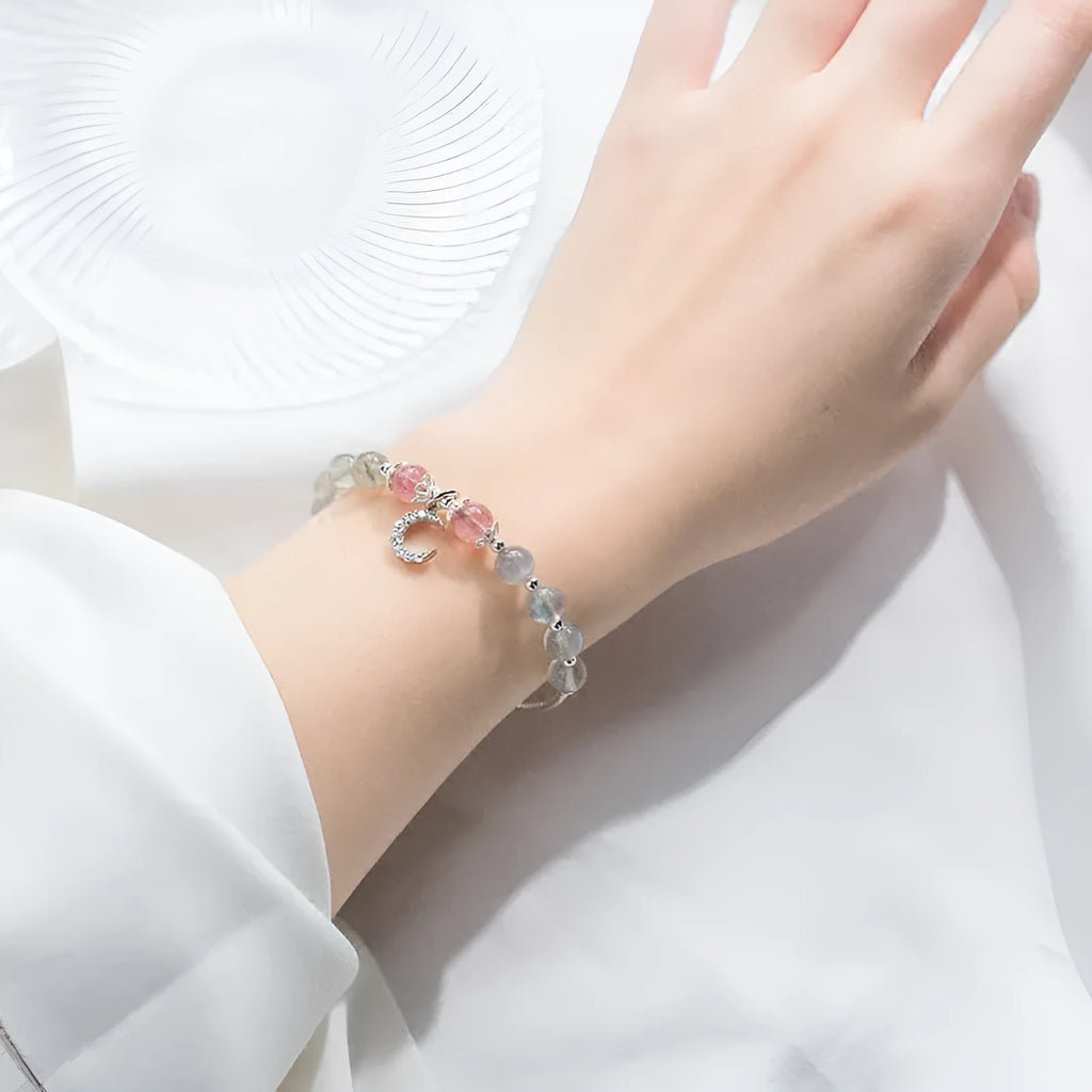 Handmade adjustable moonstone bracelet with silver crescent moon charm and crystal bead on a wrist.