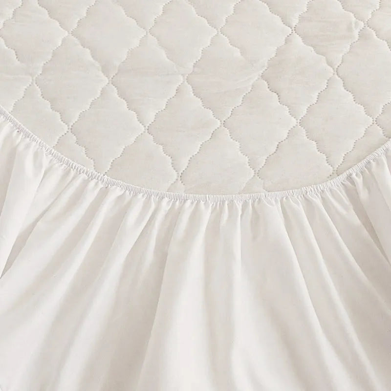Diamond lattice quilted waterproof mattress protector fitted sheet in a solid colour on a bed.