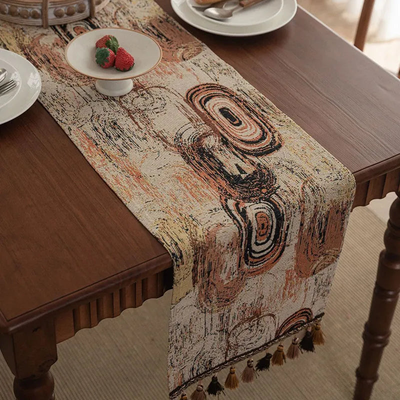 Dark blue striped table runner with jacquard bouquet pattern and tassel ends on a wooden table.