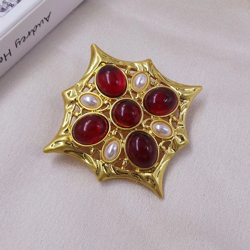 Close-up of a metallic medieval baroque cross brooch with crystal details on a dark background