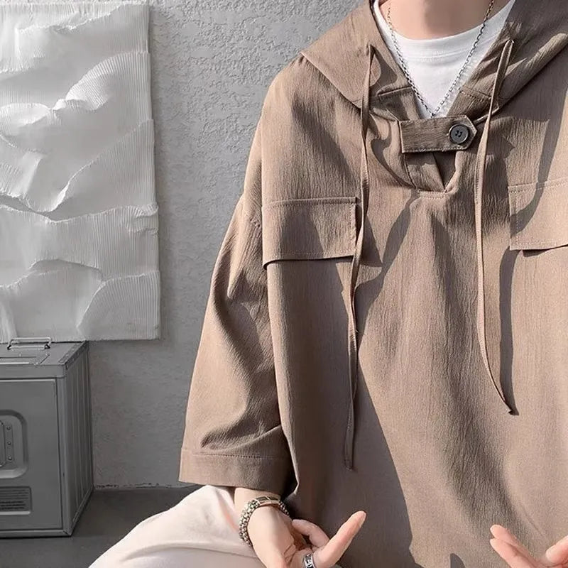 Man wearing a loose fit hooded short sleeve t-shirt in a solid colour for summer.