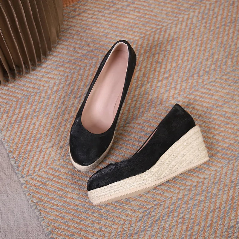 Black wedge heel pumps with thick rope-textured sole and shallow mouth opening.
